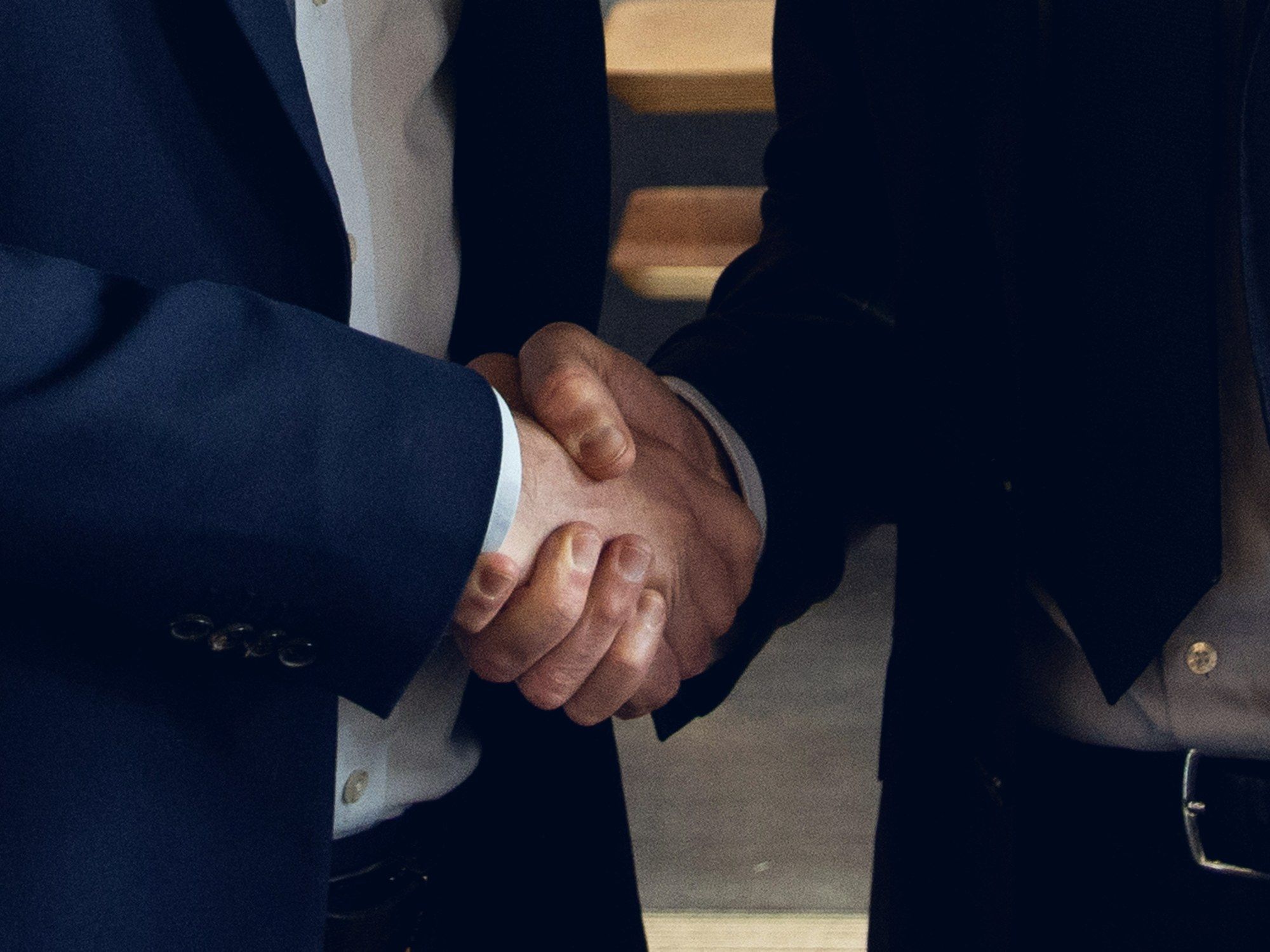 Two people in suits shaking hands.